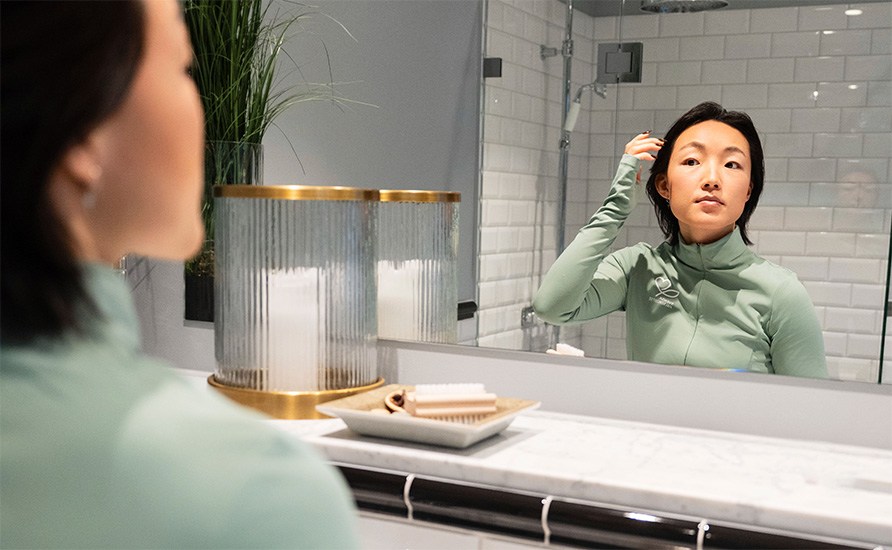 Nainen katsoo kasvojaan kylpyhuoneen peilist.