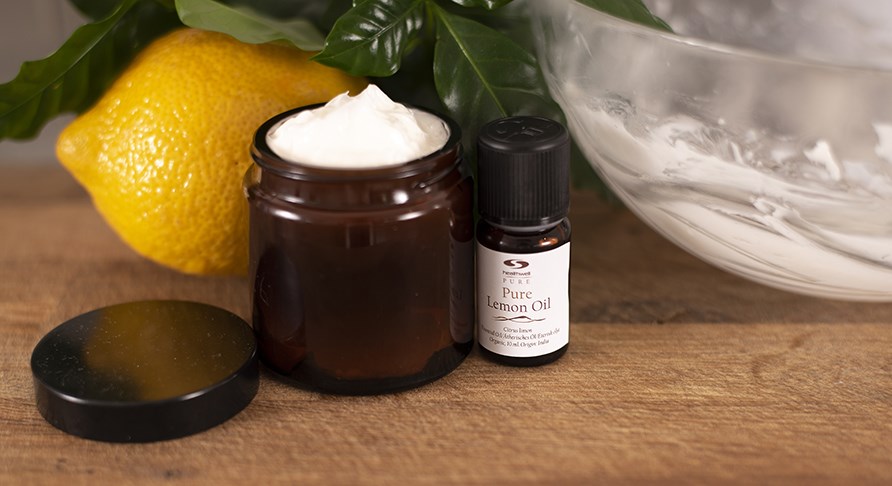 Kotitekoinen vartalovoide ruskeassa lasipurkissa, vieress� sitruuna ja puhdasta sitruuna�ljy�.