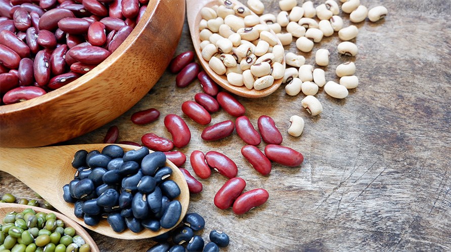 Erilaisia papuja aseteltuna lautaselle ja puulusikoille puup�yd�lle.