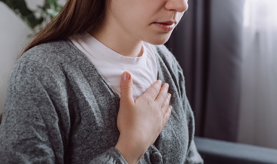 Nainen, joka pit�� k�tt��n rintakeh�n p��ll�.