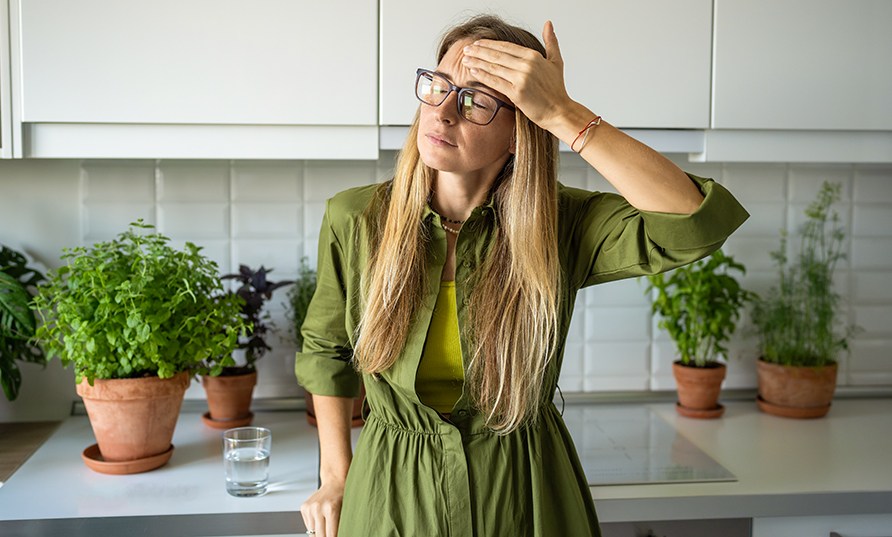 Nainen seisoo keittiss vihreiden kasvien edess ksi otsalla.