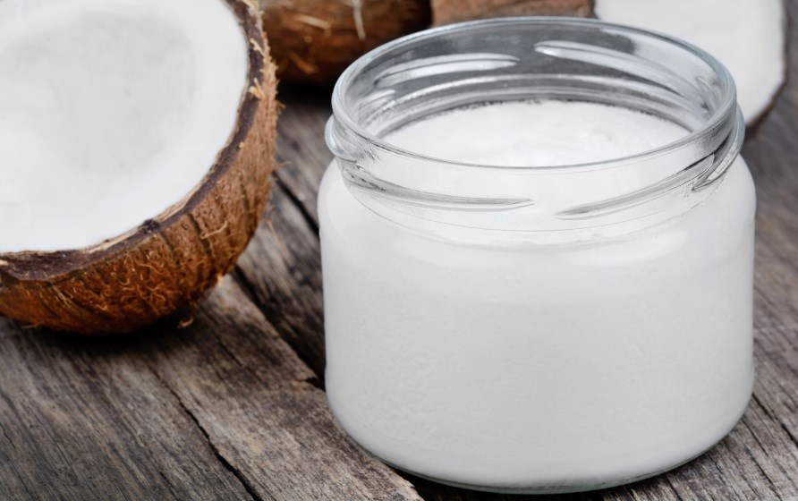 Kookosöljyä lasipurkissa puolikkaan kookospähkinän vieressä. Kookosöljyä lasipurkissa puolikkaan kookospähkinän vieressä.