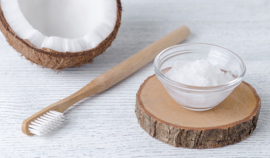 Kookosöljyä lasikulhoon, hammasharja yhdessä puolikkaan kookospähkinän kanssa. Kookosöljyä lasikulhoon, hammasharja yhdessä puolikkaan kookospähkinän kanssa.