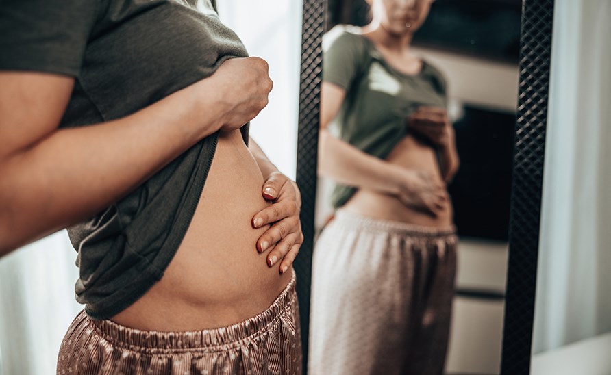 Nainen pitää kättään turvonneen vatsan päällä. Nainen pitää kättään turvonneen vatsan päällä.